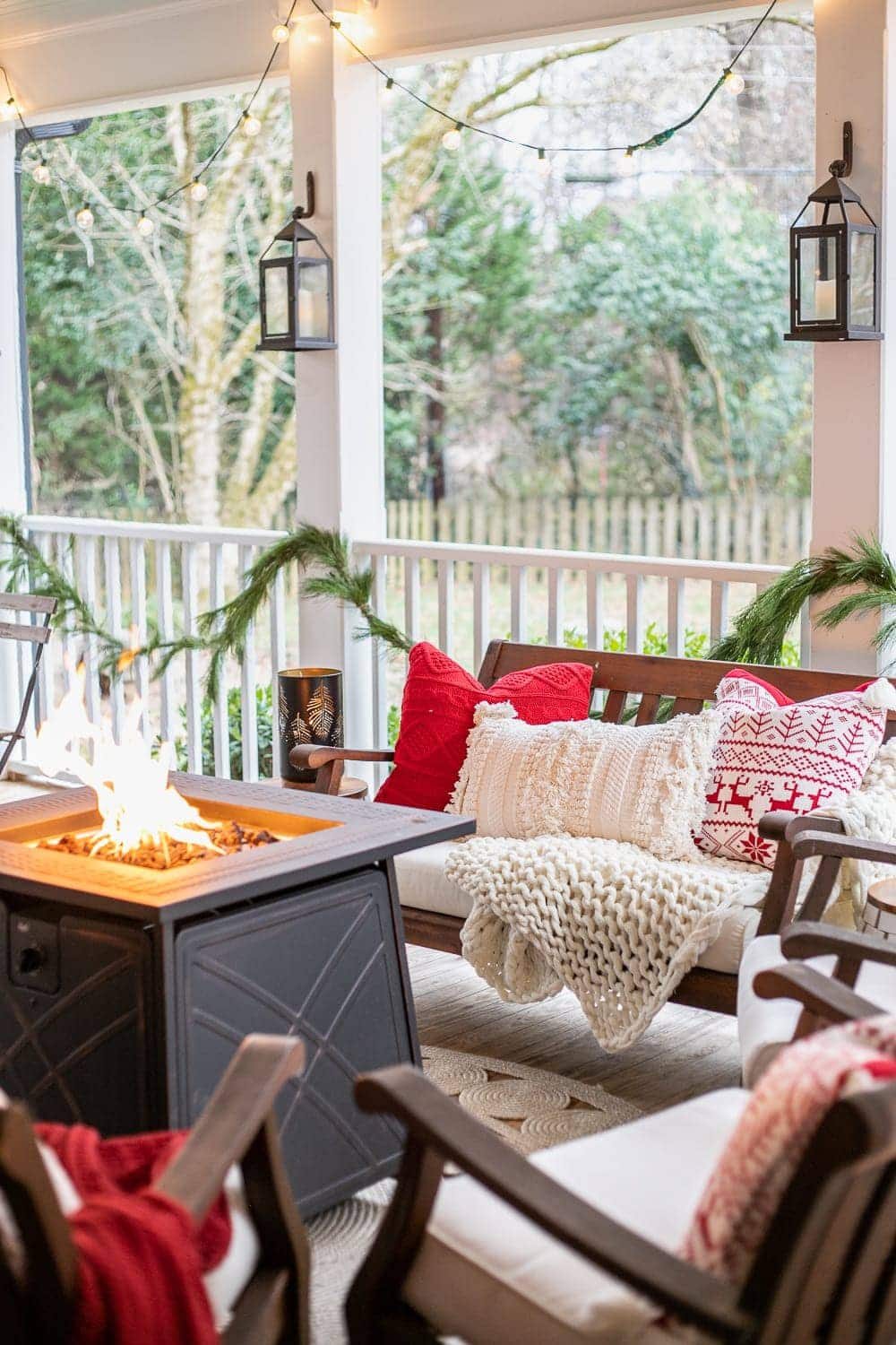 Cozy Christmas back porch with fire pit table, lanterns, and string lights