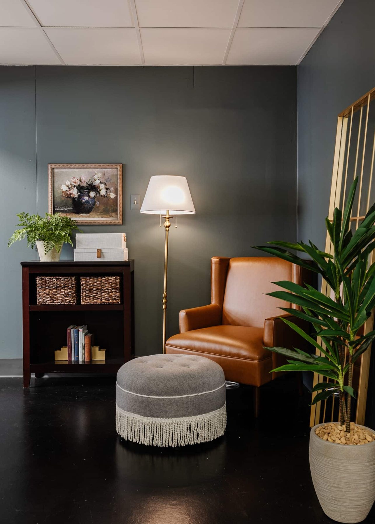 leather armchair and gray fringe footstool in a reading corner in an office