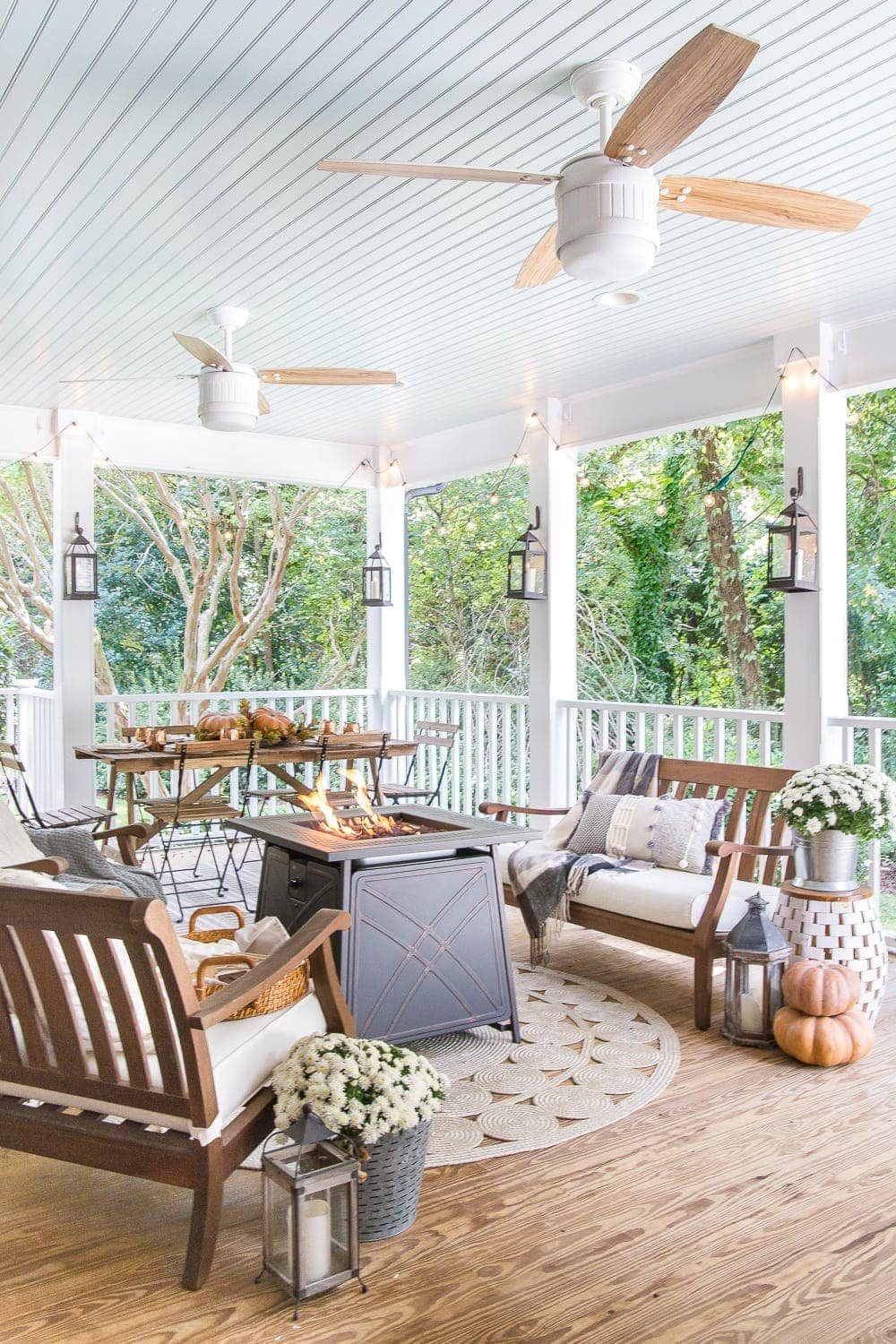 Cozy fall porch with pumpkins, a gas fire pit, lanterns and string lights