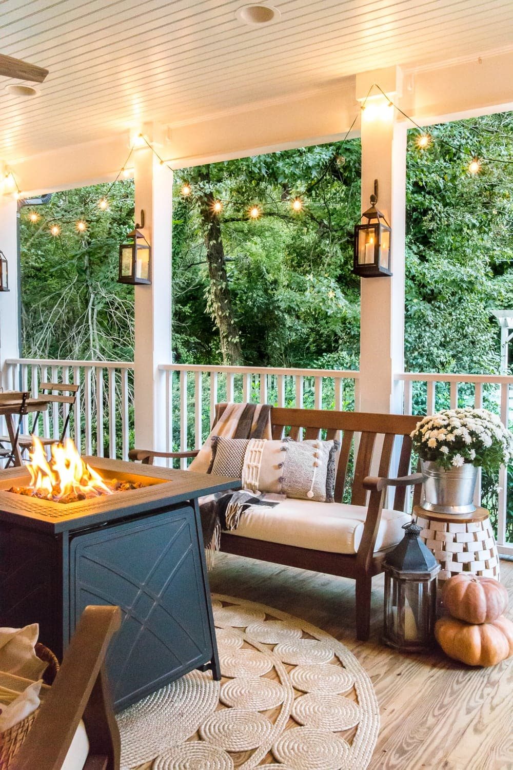 cozy fall porch with fire pit, string lights, and lanterns