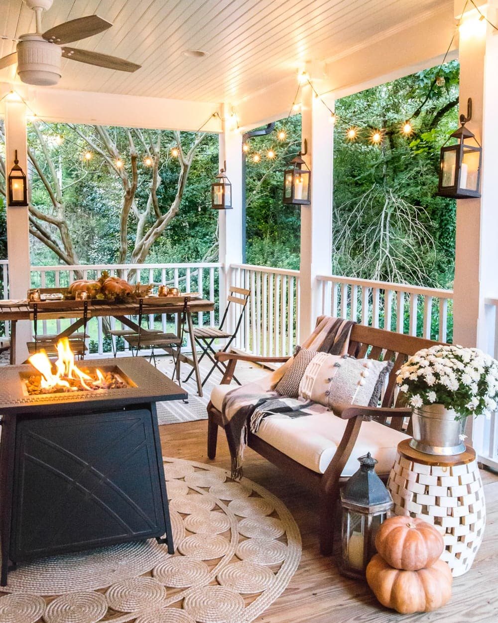 cozy fall porch with fire pit, string lights, and lanterns