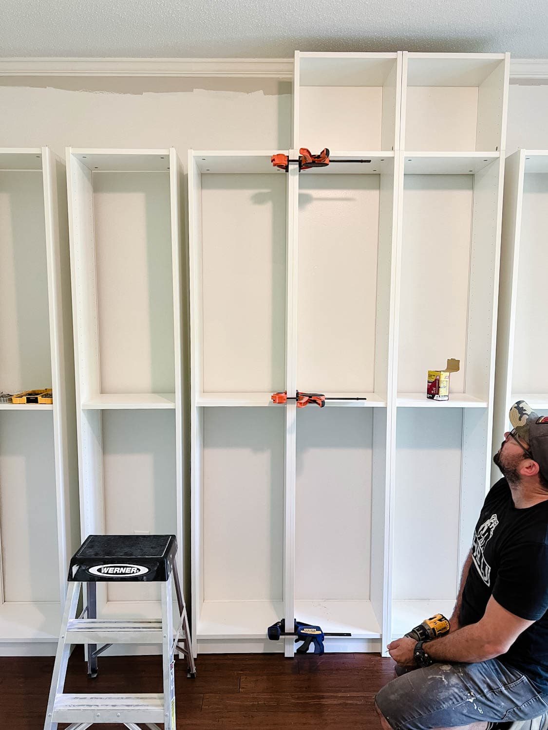 using clamps to keep bookcases together to attach them with wood screws to make diy built in bookshelves