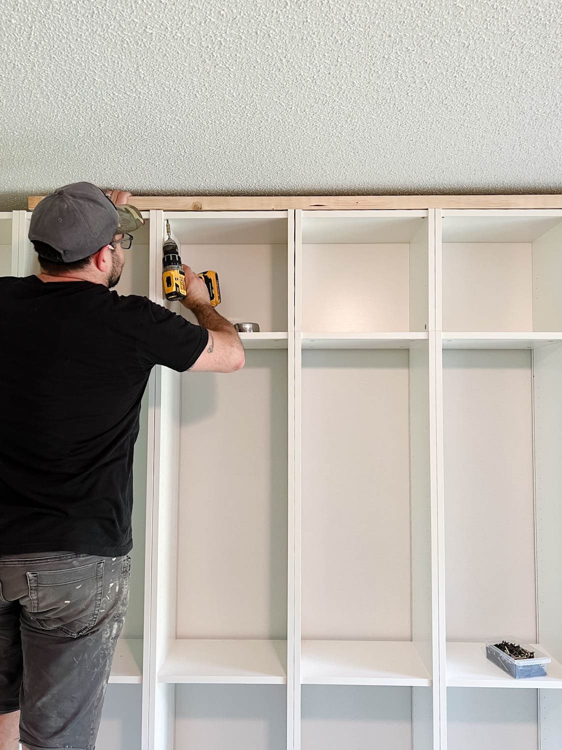 adding a 2x4 board to the top of bookcases to fill the gap below the ceiling for DIY built in bookshelves