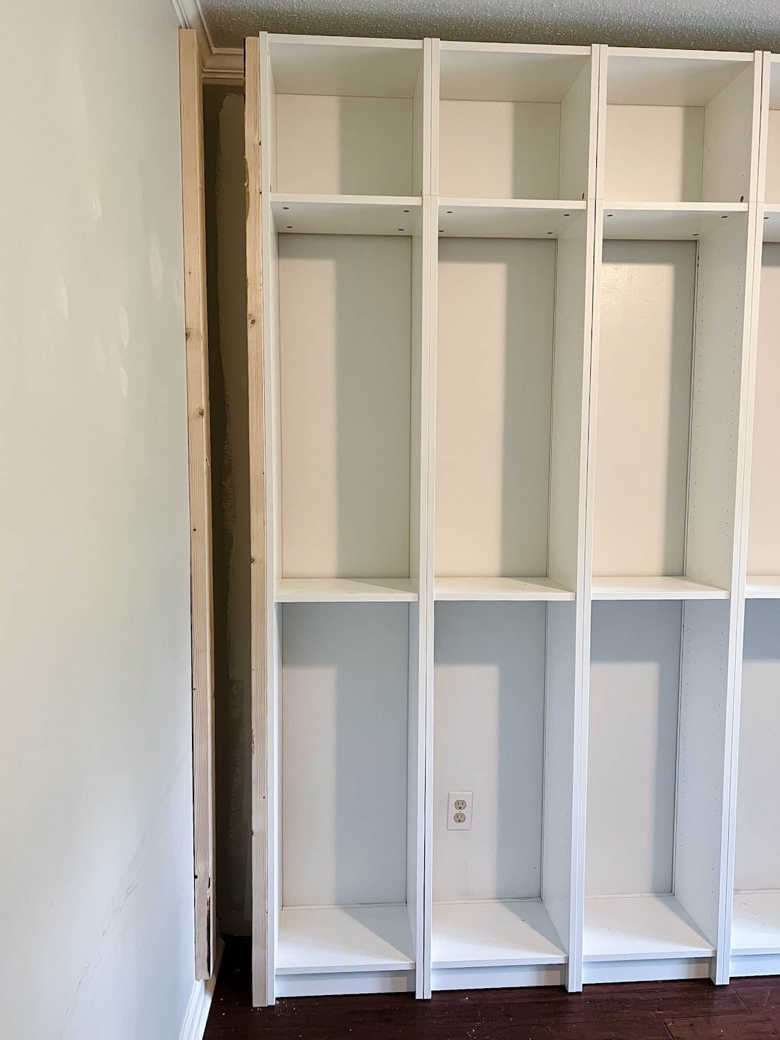 using 2x4 boards to brace sides and fill gaps to make bookcases look built in for the IKEA Billy bookcase hack