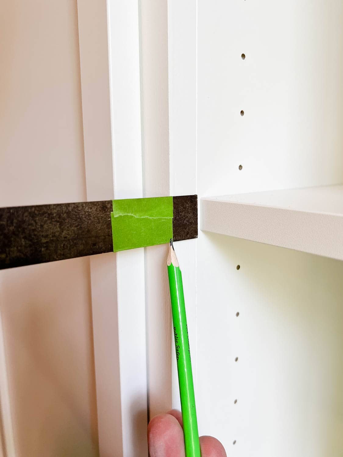 using tape on a combination square to mark new depth of hinge holes