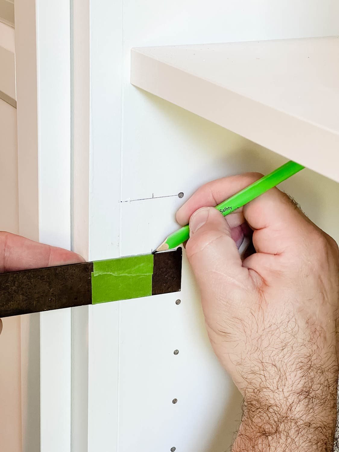 using a combination square to mark new holes for door hardware