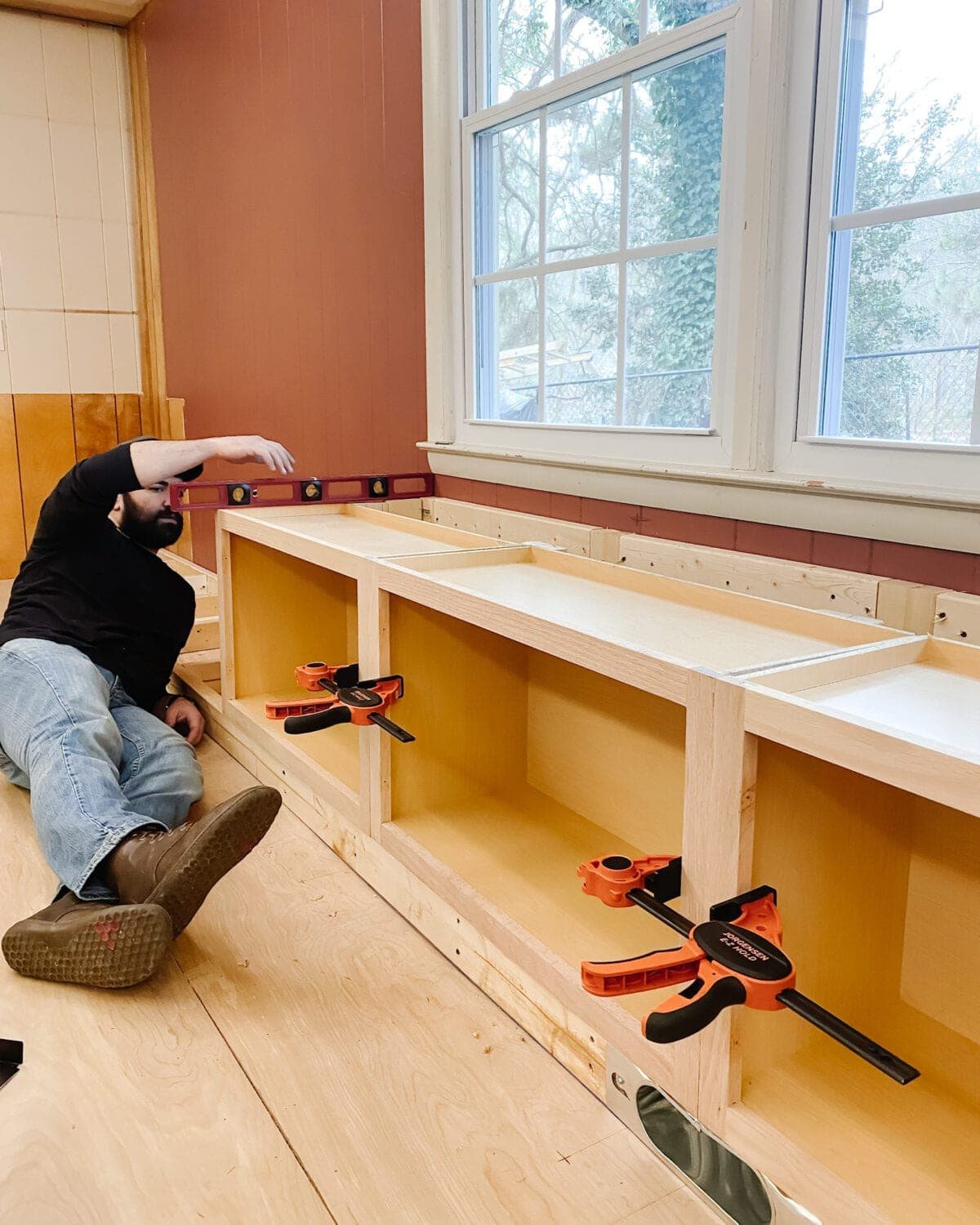 A step-by-step tutorial to build DIY built in cabinets and a window seat using inexpensive stock kitchen cabinets.