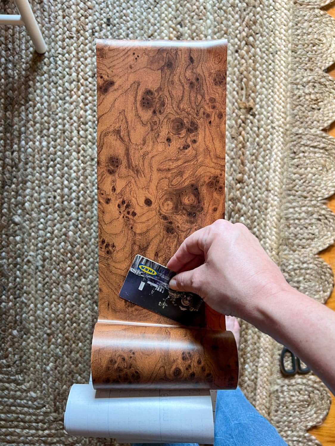 smoothing out burl wood contact paper to dresser drawer front