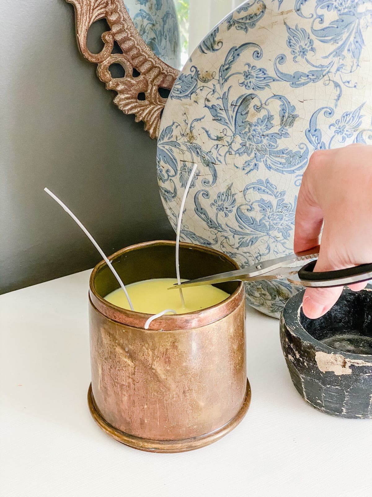 cutting wicks on a DIY candle made from an antique brass canister