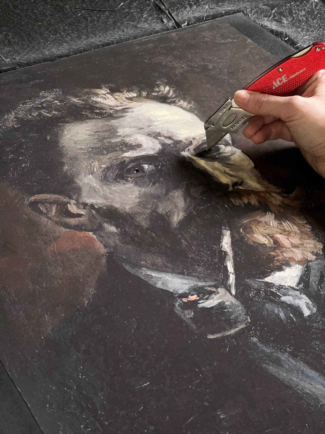 cutting eyes out of art print with a utility knife