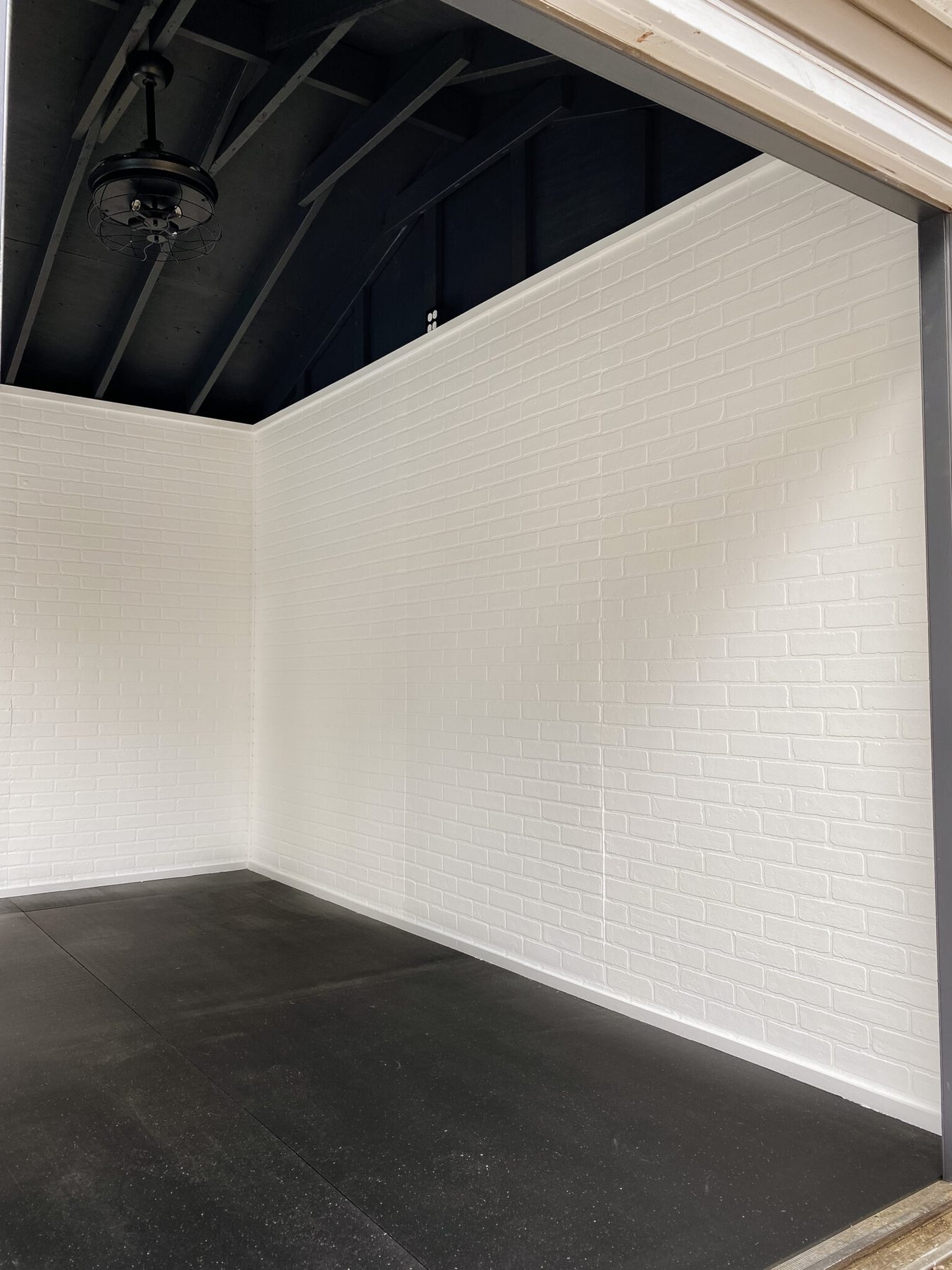 home gym with white faux brick wall panels and black ceiling