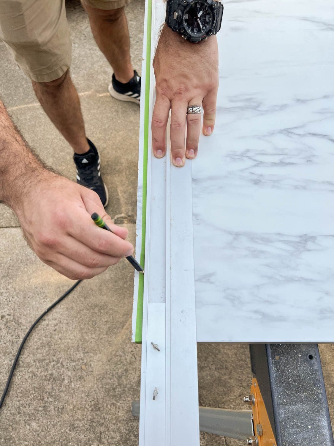 marking straight edge on masking tape on laminate faux marble countertop to be cut
