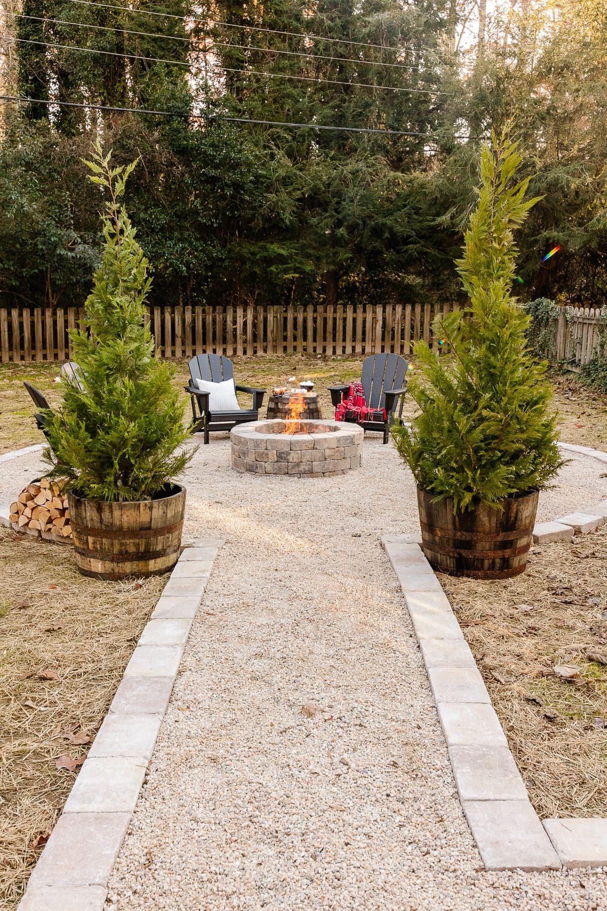 backyard Fire pit with pea gravel, stone edge, and black adirondack chairs