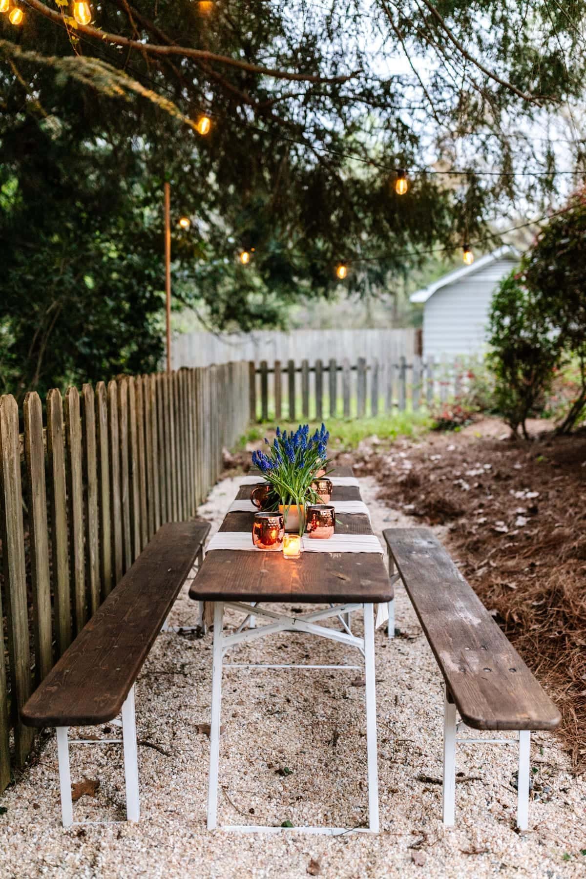 Hanging string lights on wooden dowels for a DIY backyard dining area