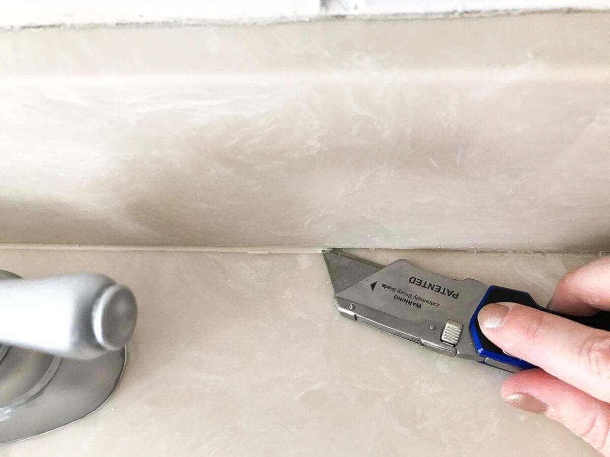 scraping away caulk for painting a countertop