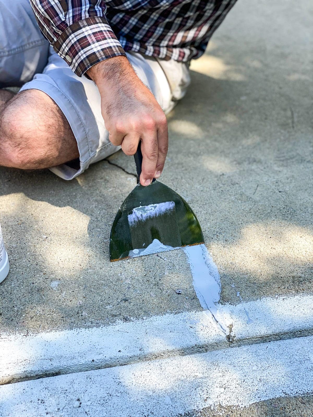 spreading concrete filler to patch cracks and holes