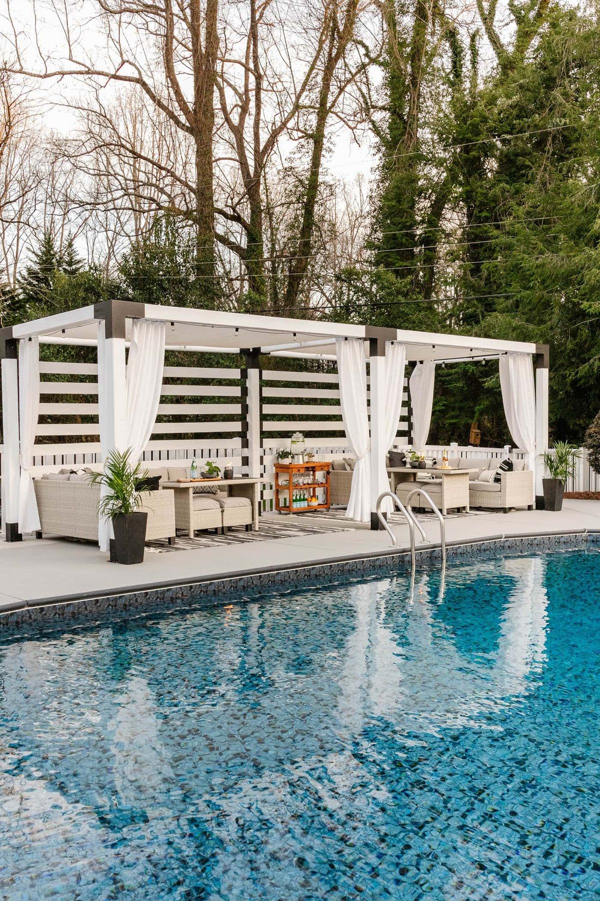 backyard swimming pool with painted concrete deck, poolside patio furniture and cabana
