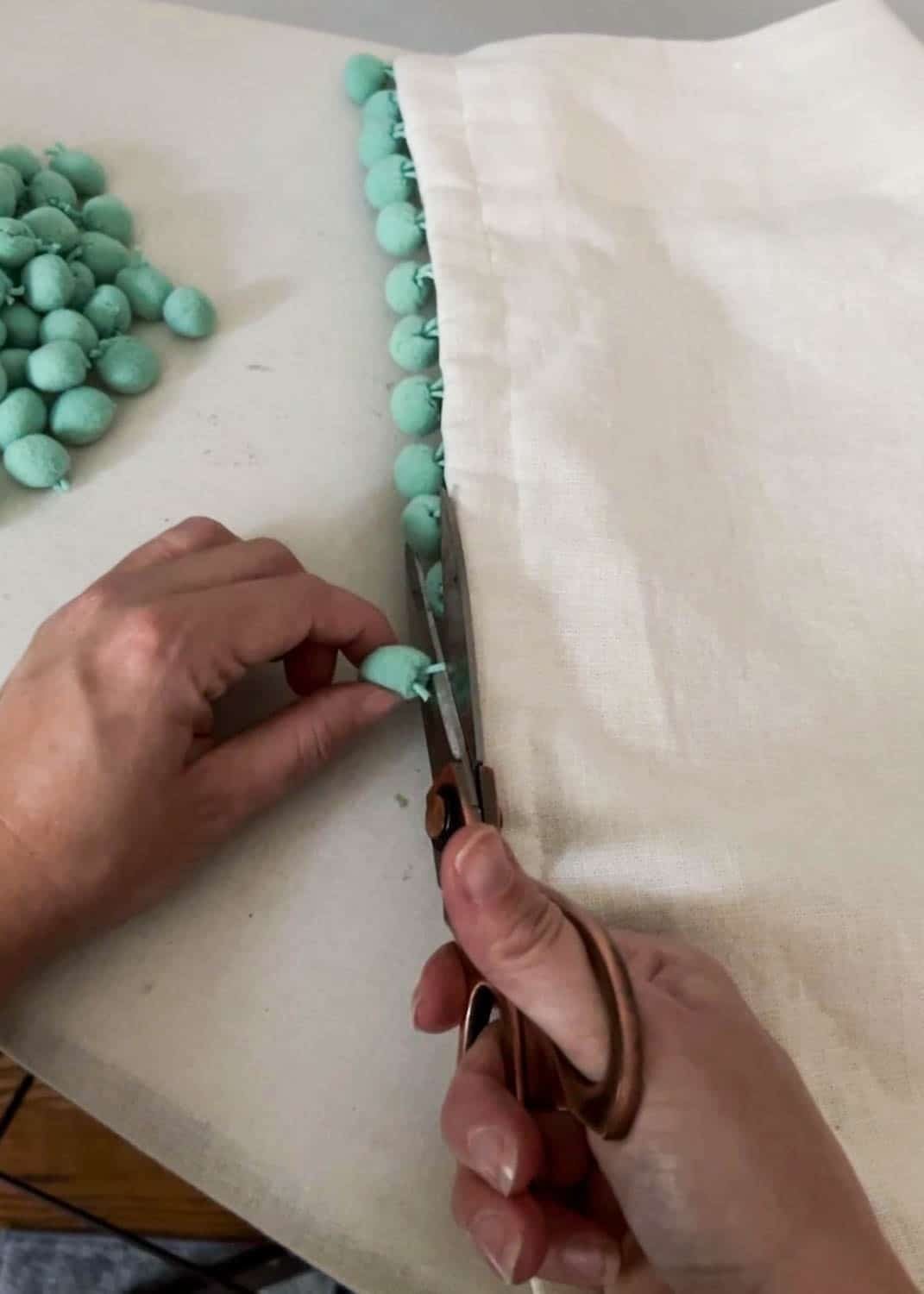 removing pom poms from curtains with scissors