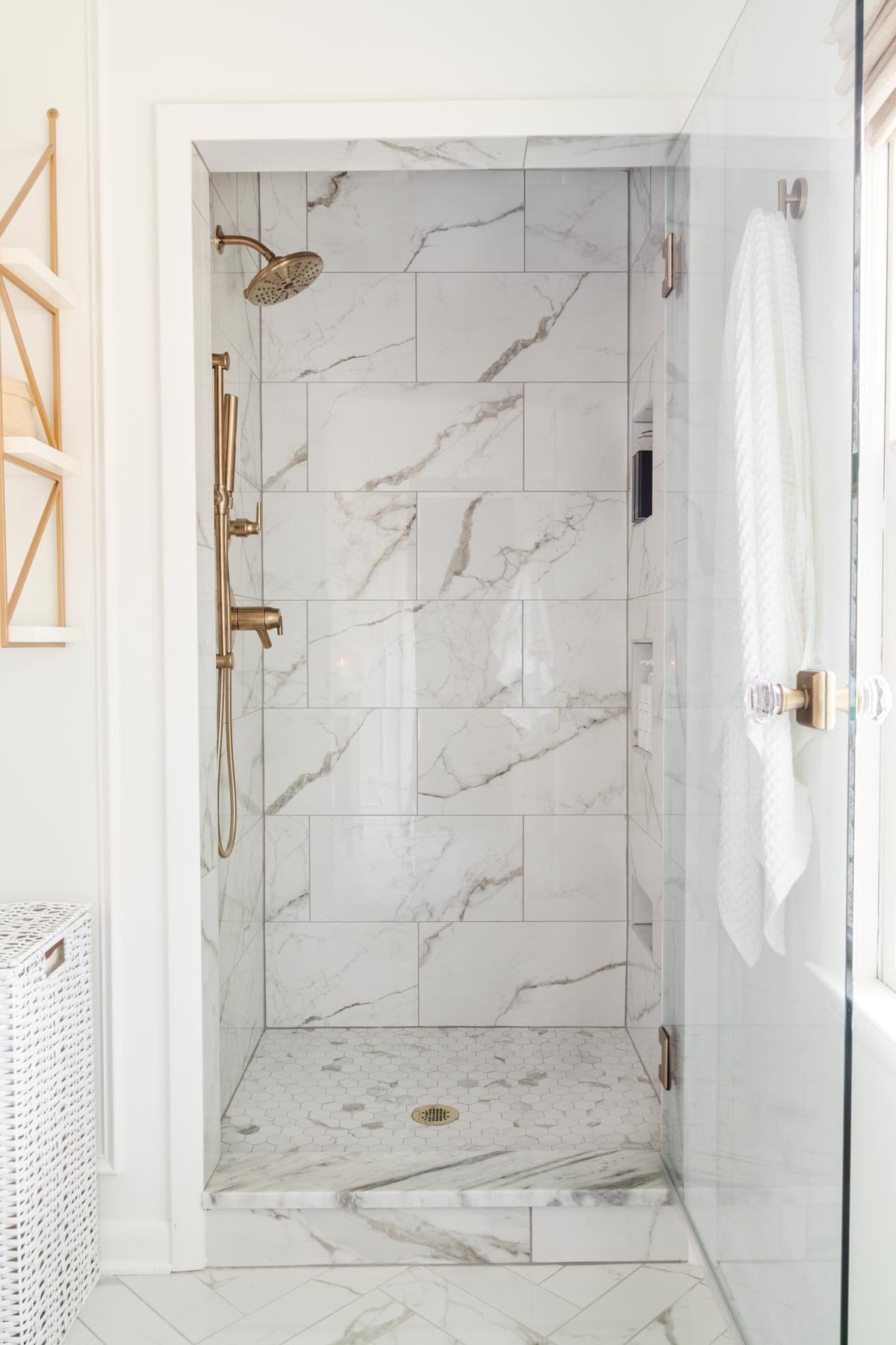 small shower with glass door and marble effect tile