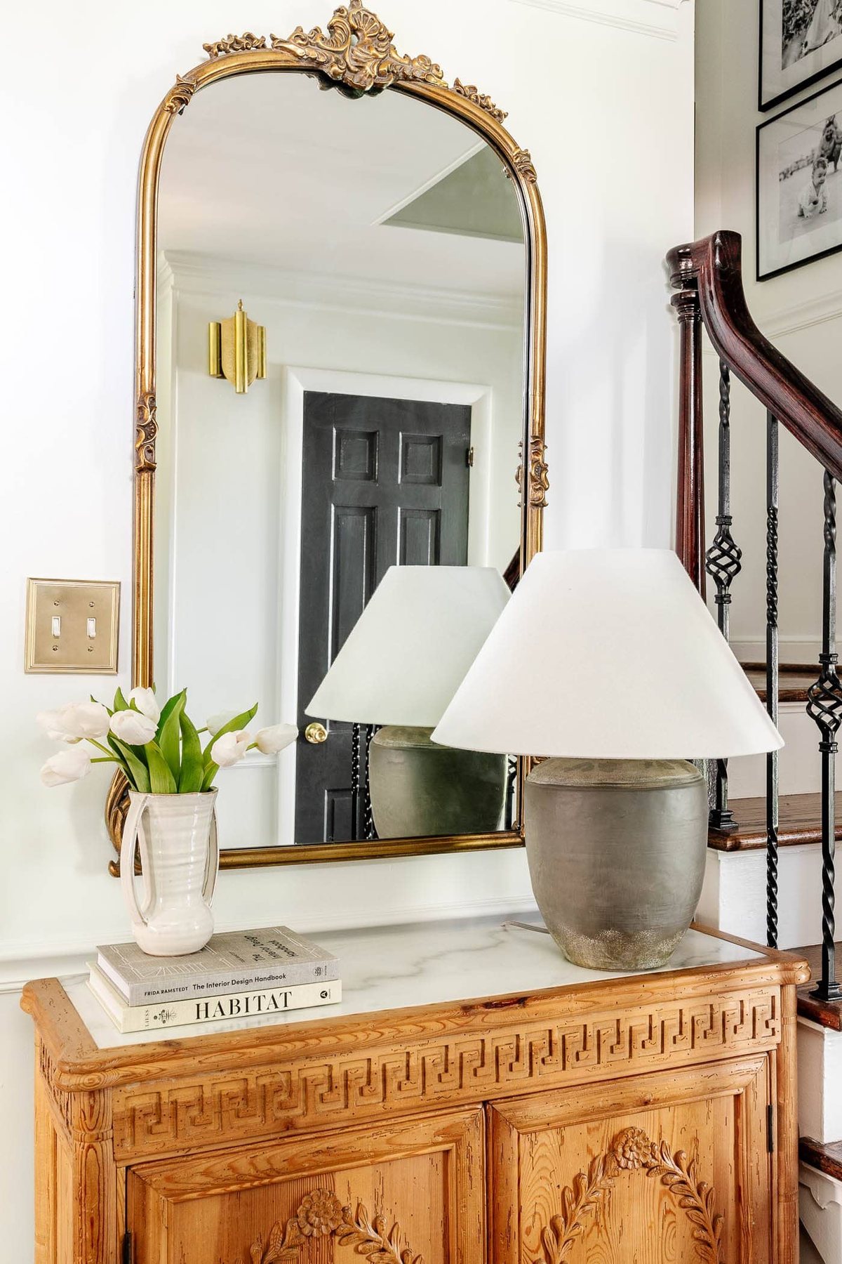 adding a stack of books underneath a vase of flowers as risers for height in decorating a foyer table