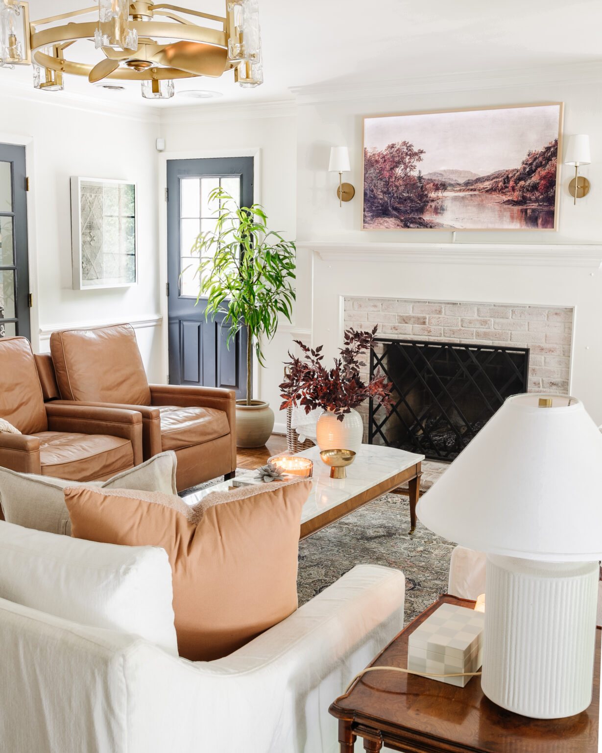 fall decorating ideas for a living room with vase of fall stems, fall art on a TV, and leather recliners