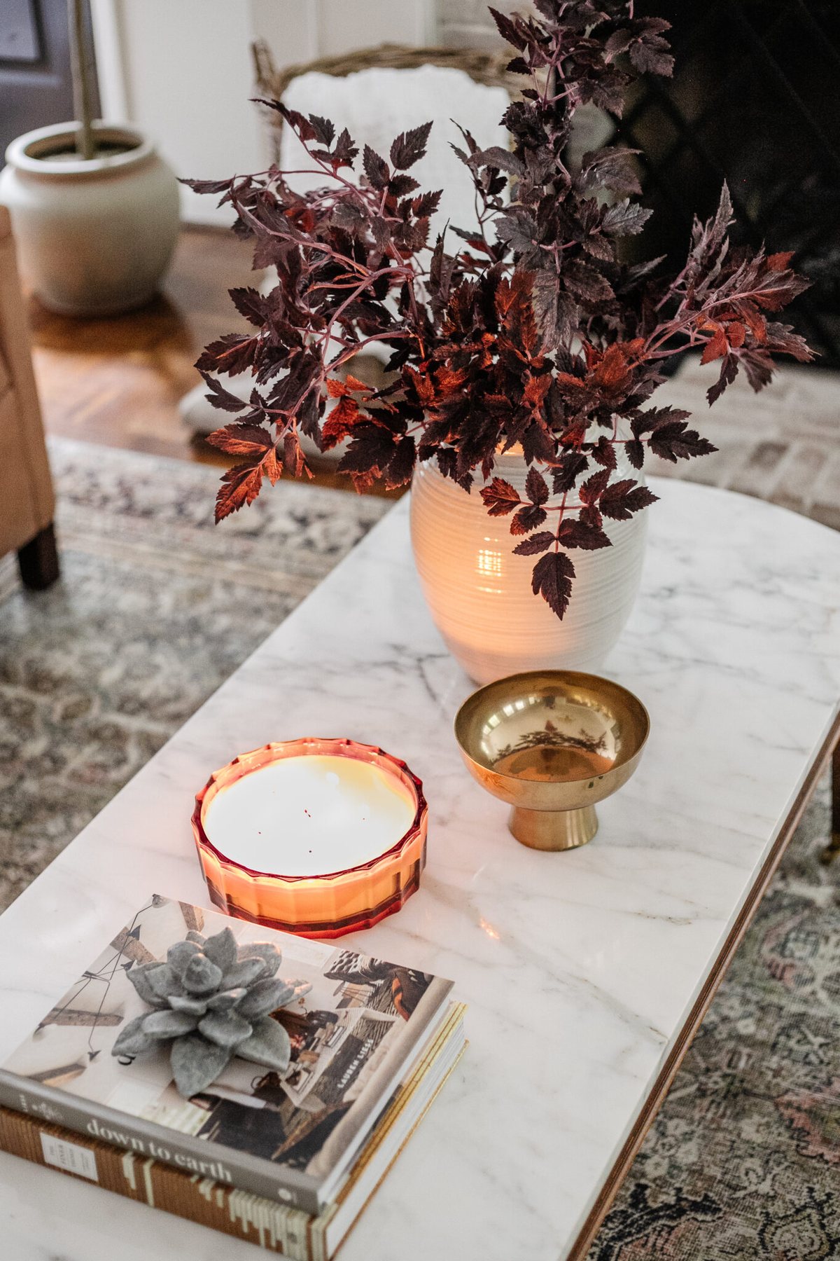 fall coffee table decor with vase of fall stems, candle, bowl, and books