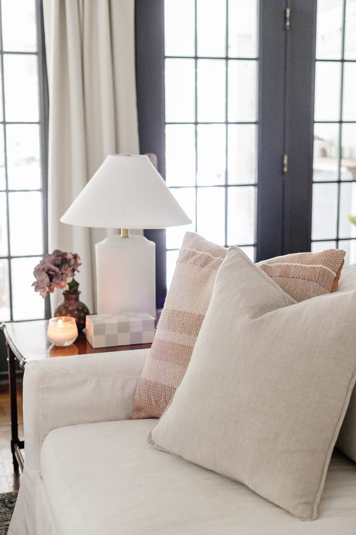 neutral throw pillows on a white couch with subtle end table decor and lamp