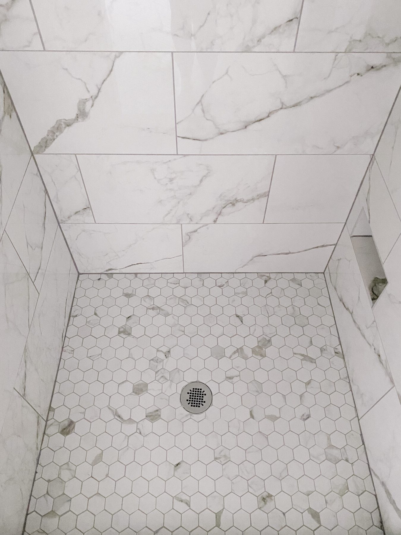 faux marble hexagon tile shower floor with gray grout
