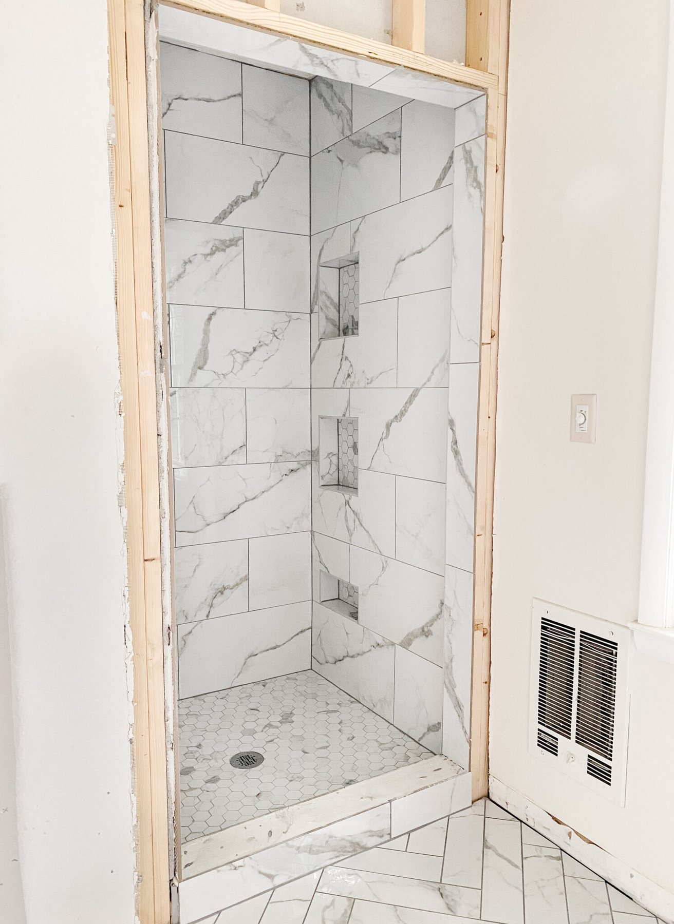 faux marble herringbone tile floor and faux marble tile shower with hexagon with gray grout