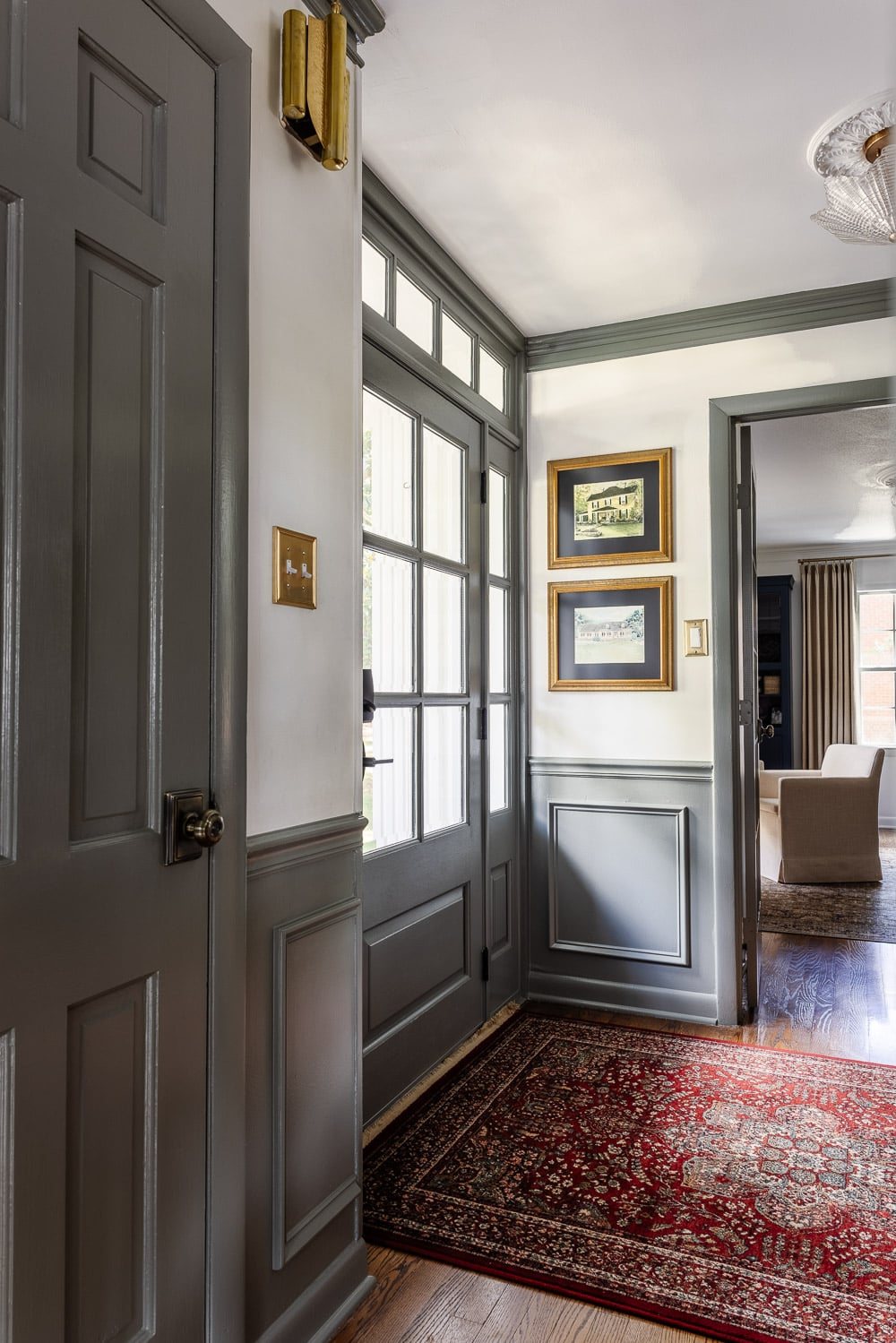 front door painted green gray in a foyer with unexpected red theory in a rug