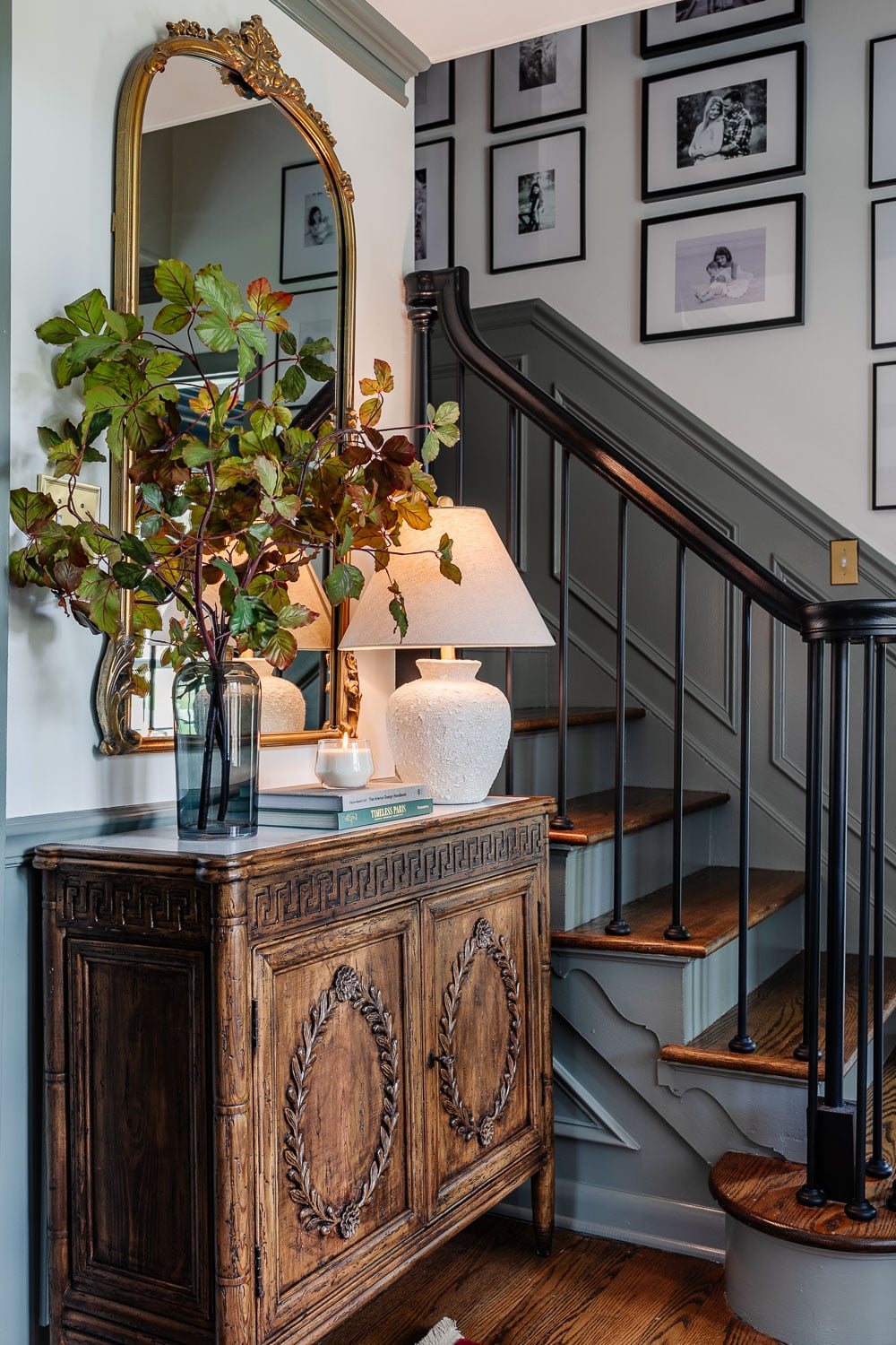 foyer decorating ideas with credenza styled with lamp, vase of stems, books, and candle
