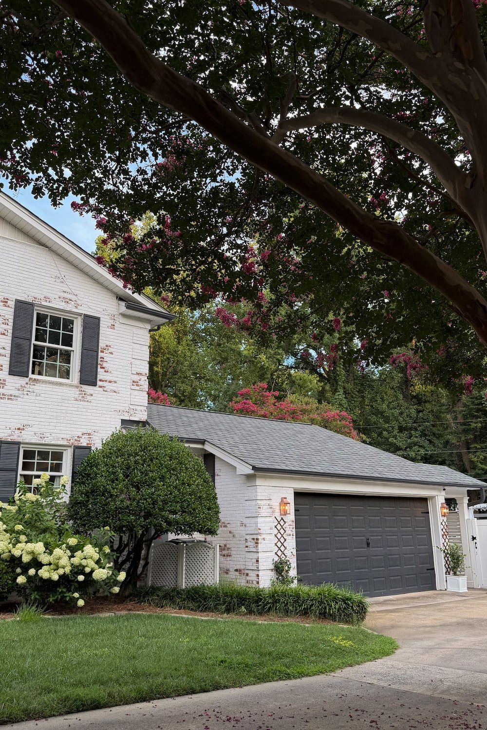 garage curb appeal with copper lanterns, star jasmine, and outdoor trash can hiding panels