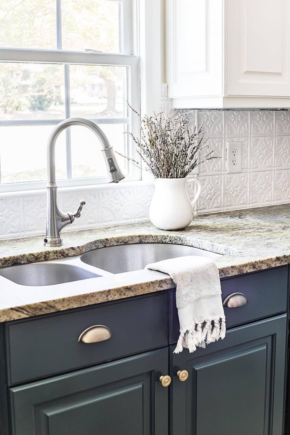 Pressed tin ceiling tile backsplash and deep green kitchen cabinets