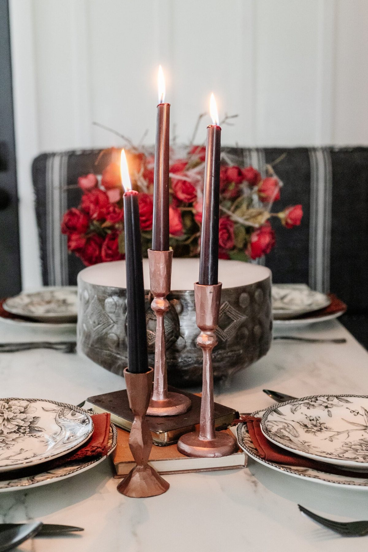 hammered copper candlesticks with black candles stacked on old books