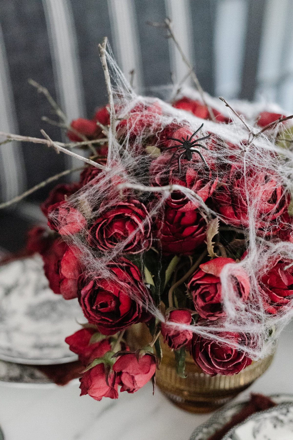 vase of red roses with spider webs for a simple Halloween flower arrangement