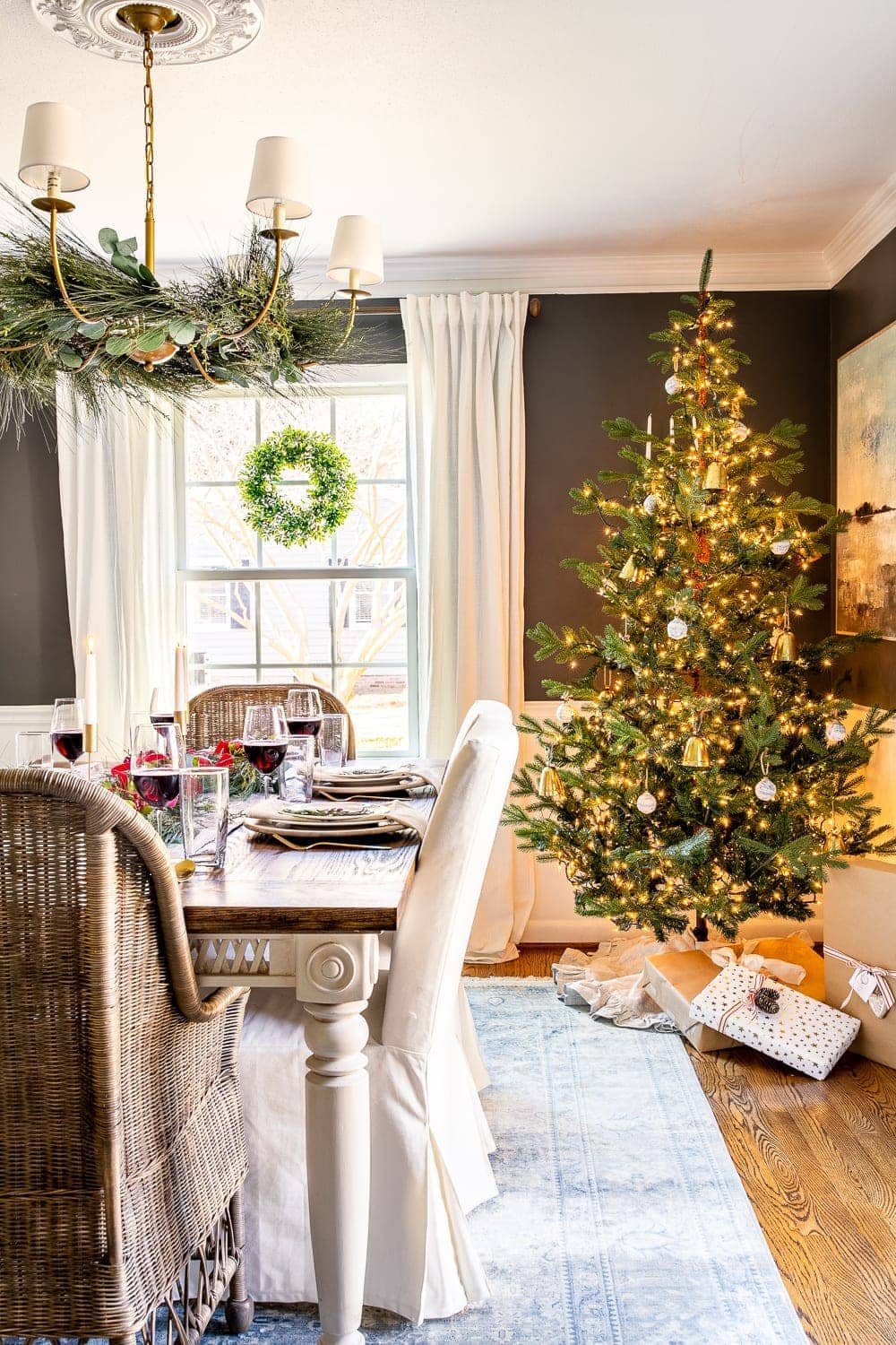 Christmas decorating ideas | Christmas tree in the dining room with garland on a chandelier and wreaths on windows