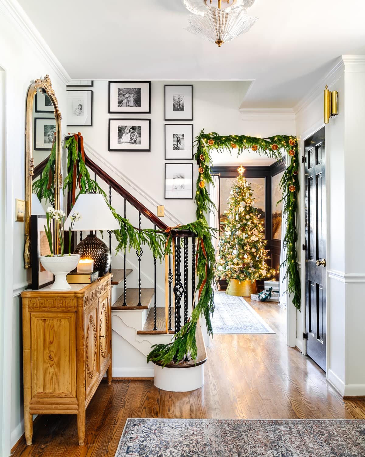 Classic Christmas decor ideas in a foyer with realistic garland on stairs and doorway