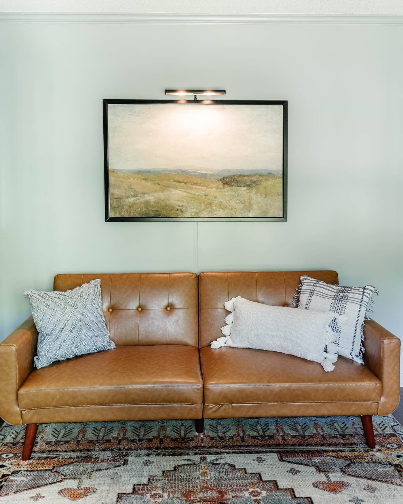 home office lounge area with faux leather futon, throw pillows, and rug