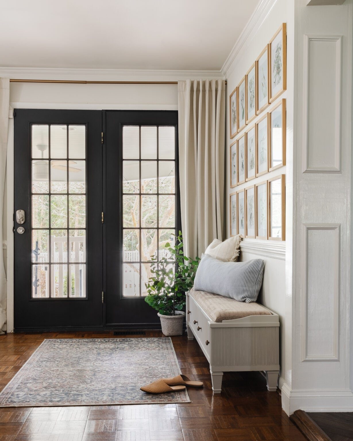 reeded shoe storage bench in an entryway with black doors and gallery wall