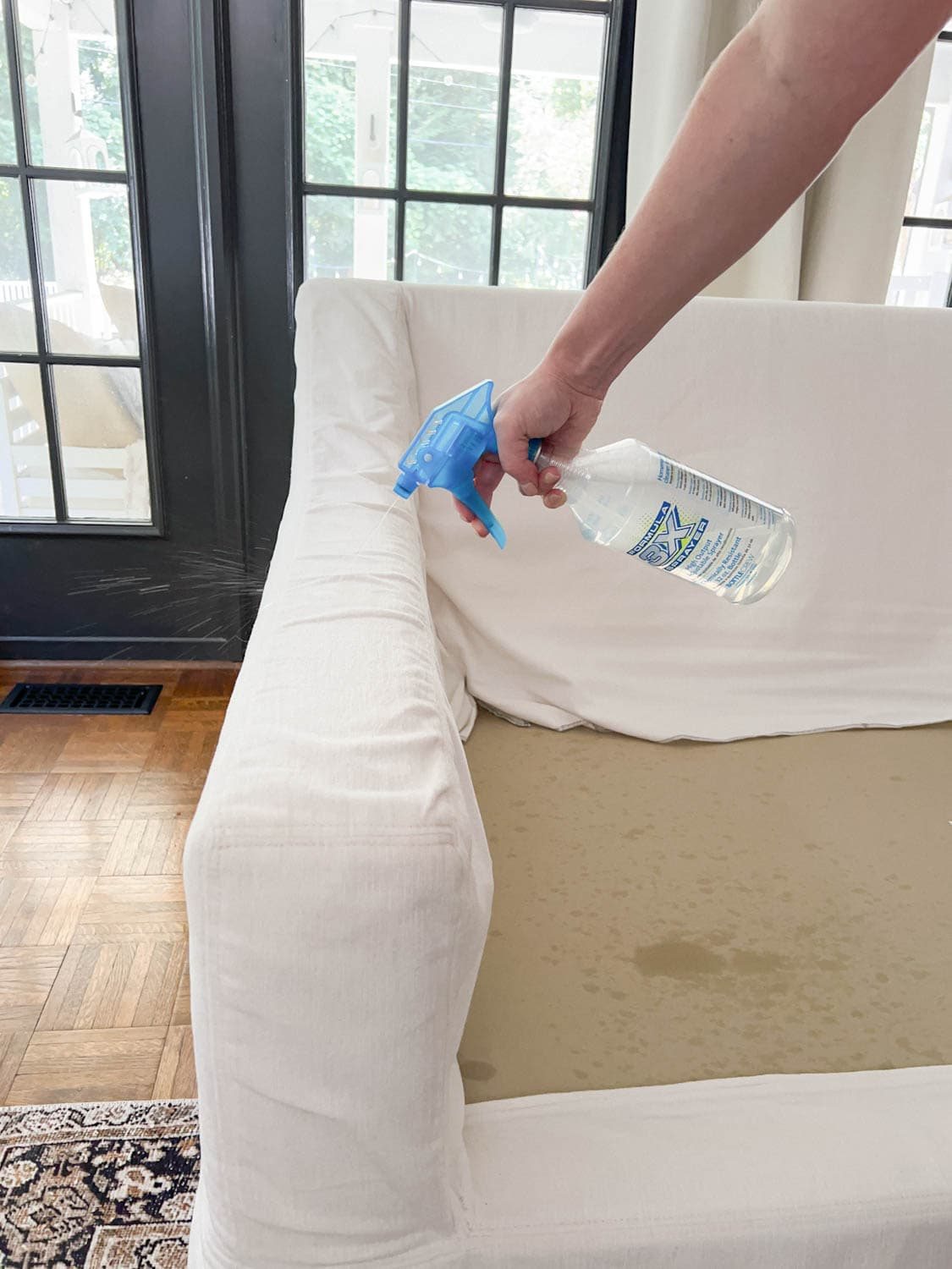 spraying DIY couch cleaner onto sofa to clean off dirt and grime