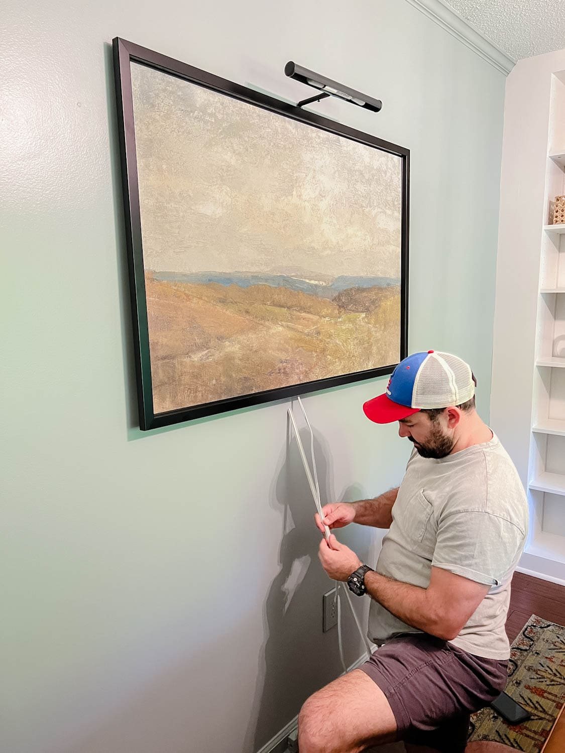 installing a picture light above a piece of art and wrapping cord in cord covers
