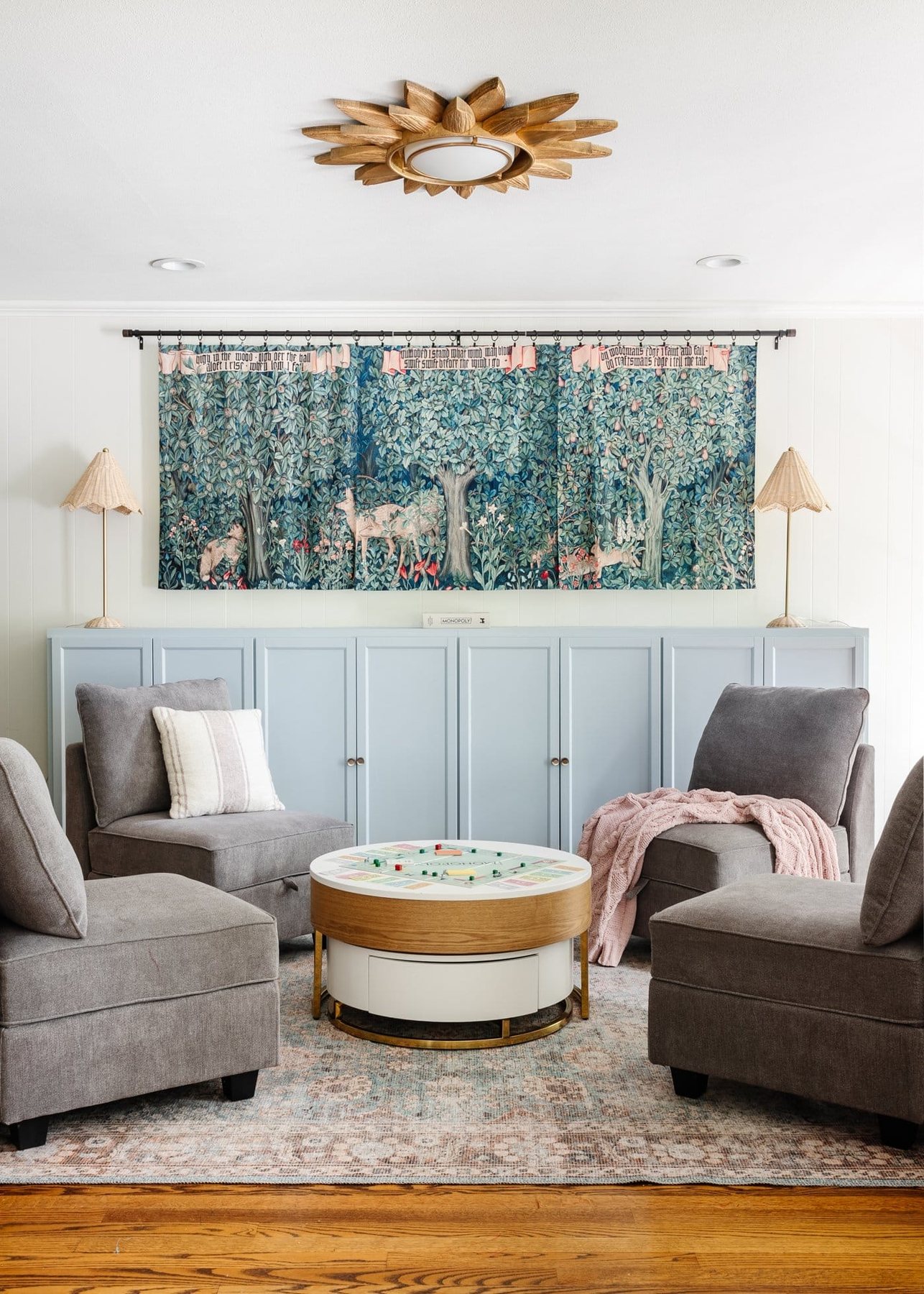 white playroom with light blue mantel and toy storage cabinets, William Morris tapestry, and storage furniture