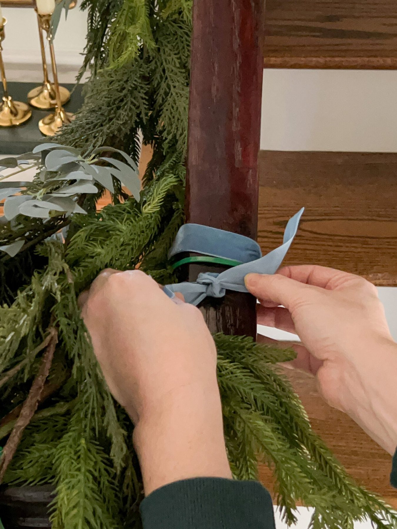 adding ribbon to cover zip ties on staircase garland