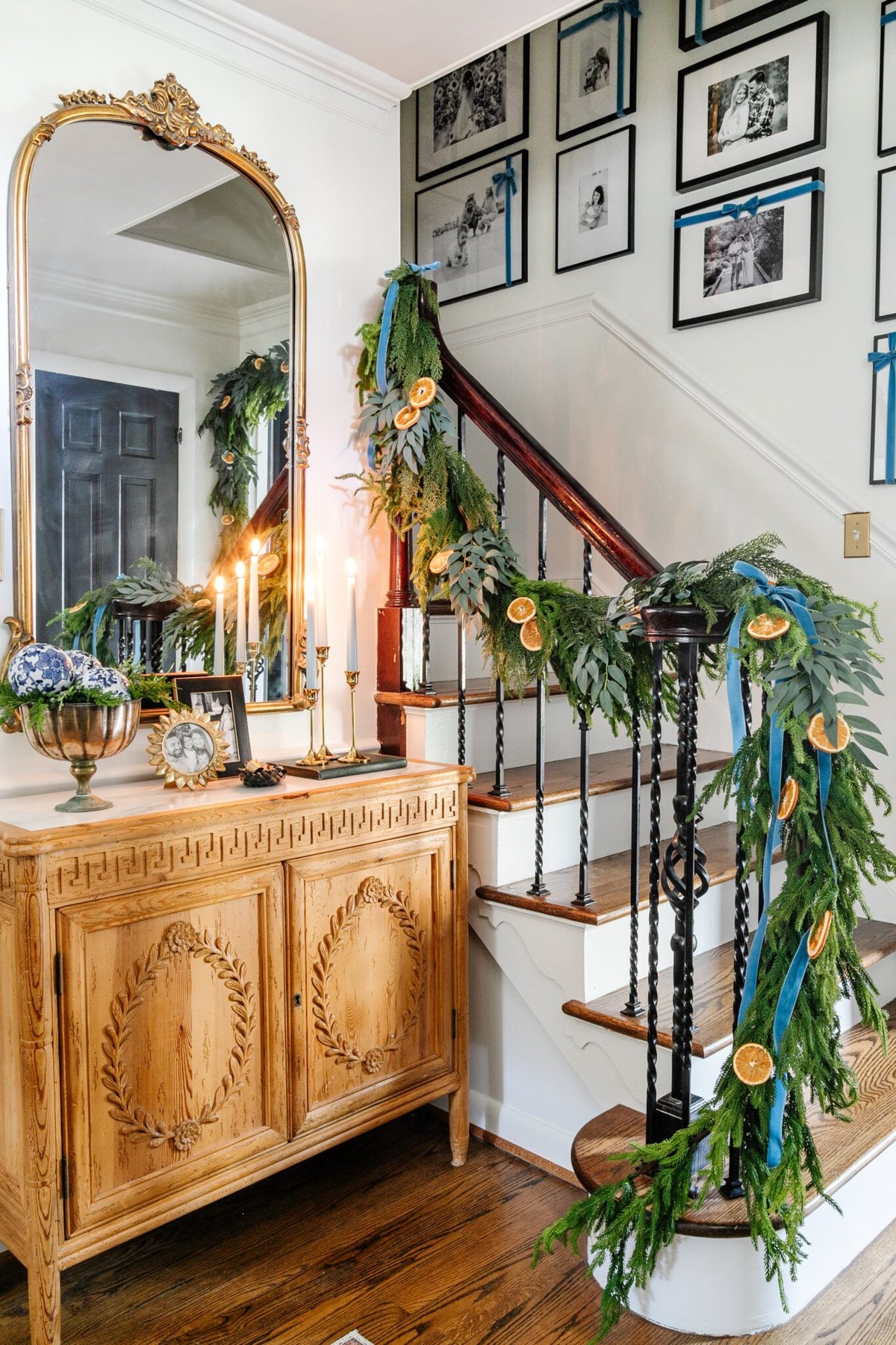 blue entryway Christmas decor with ribbon hanging from garland on stairs