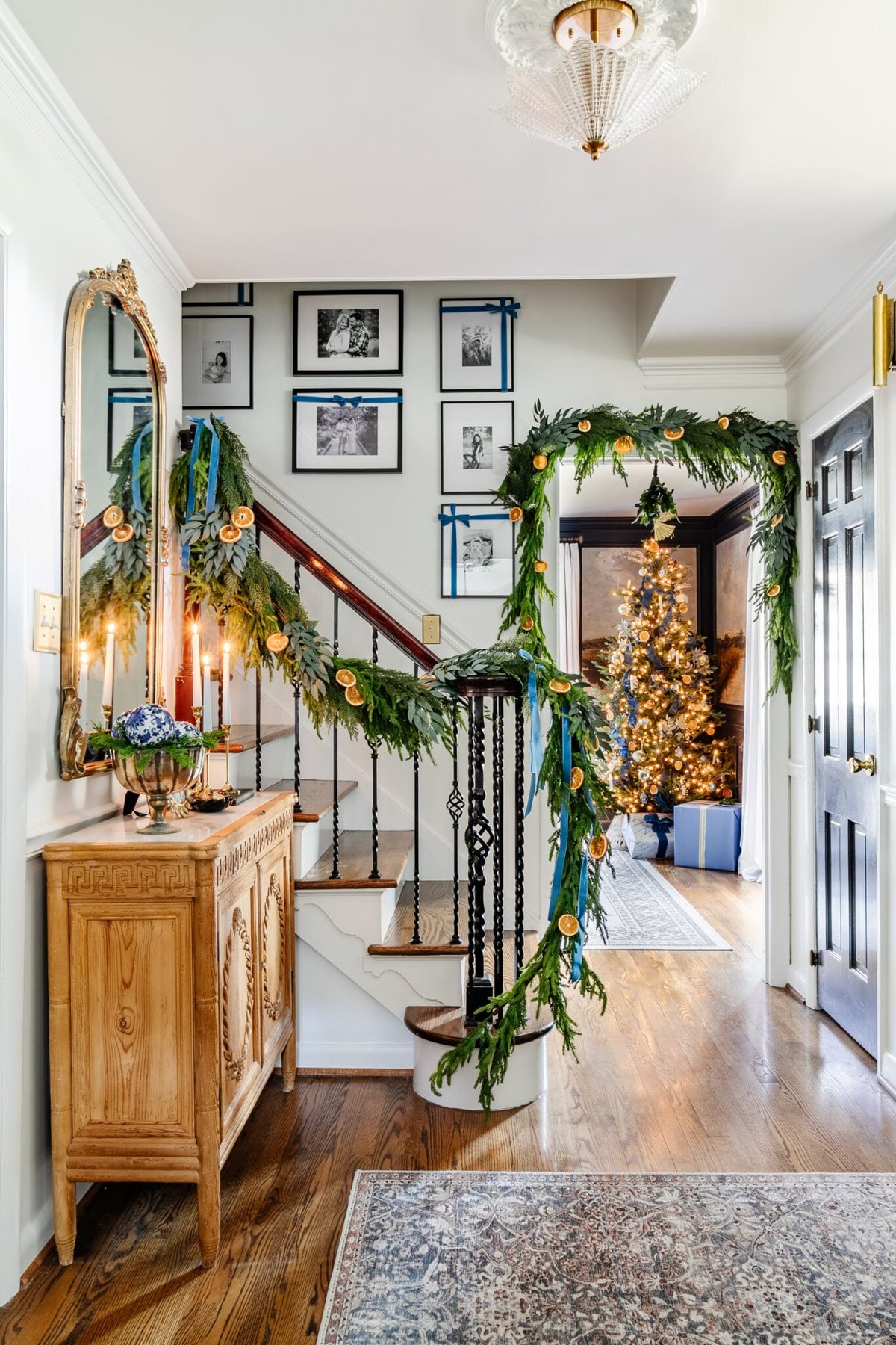 blue entryway Christmas decor with Christmas tree peeking through doorway