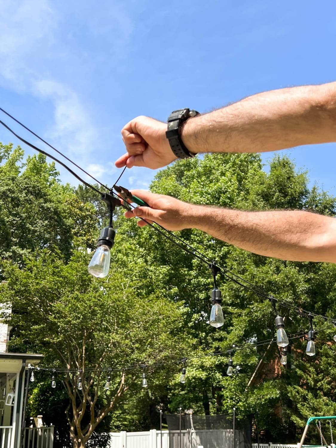 snipping zip tie ends to attach string lights to cable
