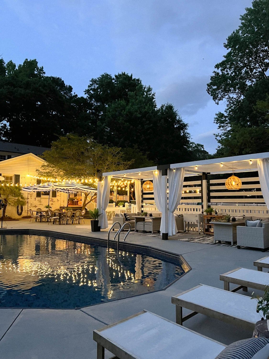 string lights around a pool at night with pergola