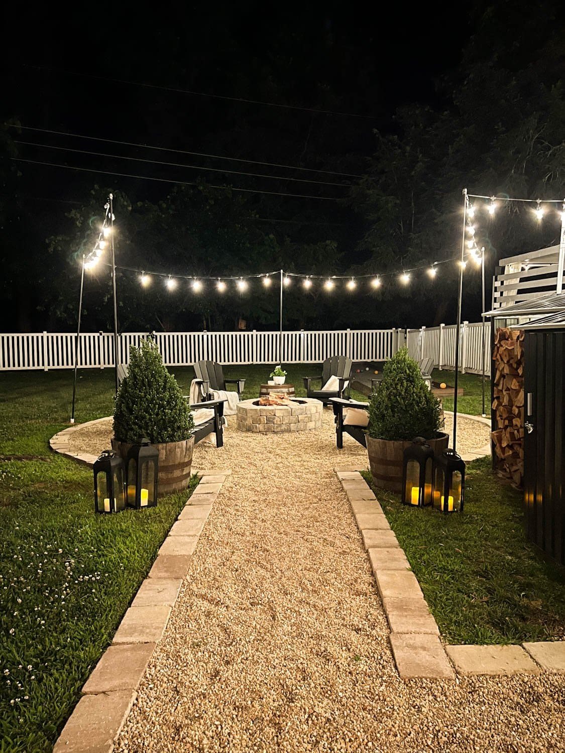 hanging string lights around a fire pit with poles at night