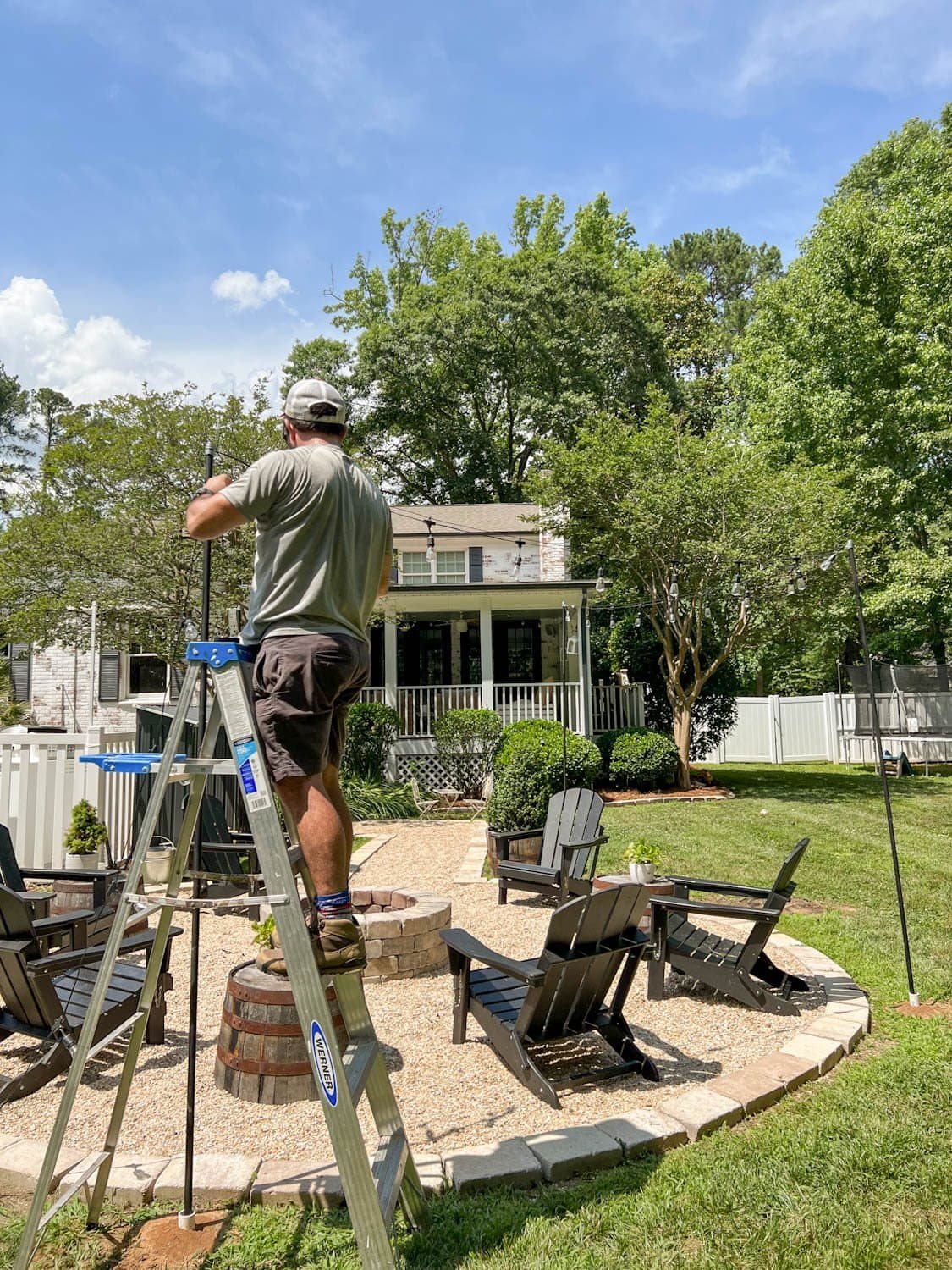attaching string lights to cable around a fire pit