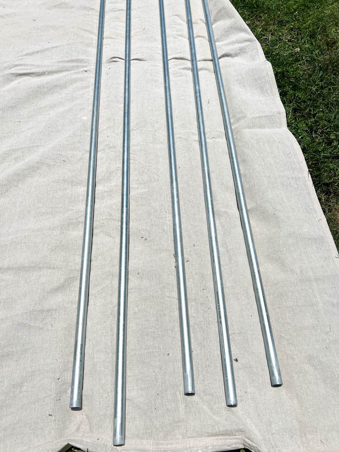 conduit poles on a drop cloth ready to be painted
